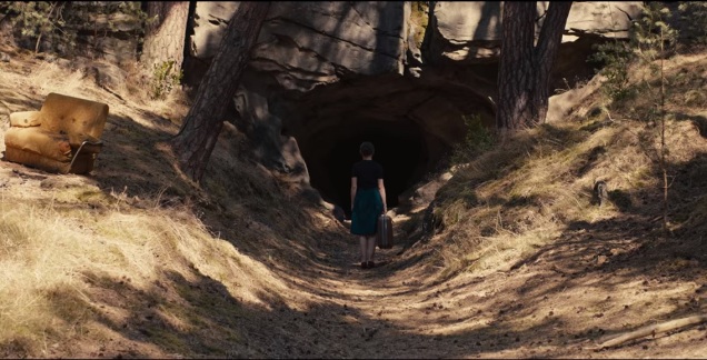 Kadr z serialu Dark, Hannah Kahnwald stoi przed jaskinią w ręku trzyma walizkę
